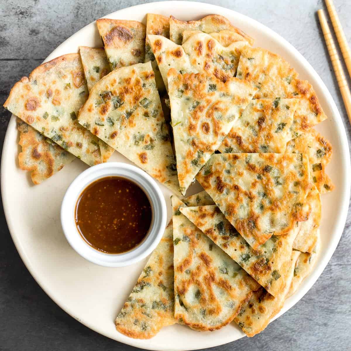 Chinese pancakes with dipping sauce on a plate.