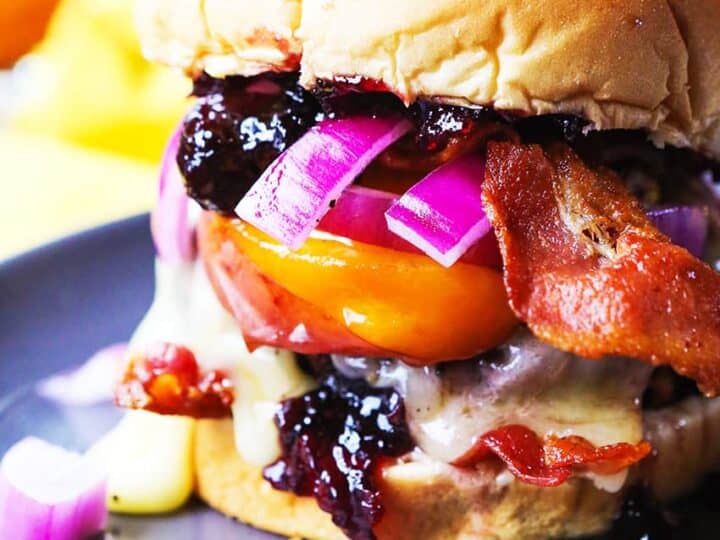 A burger with bacon and onions on a plate.