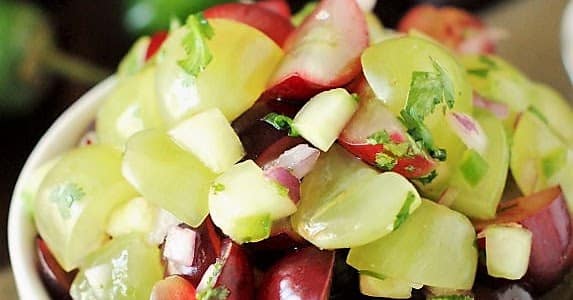 A bowl full of grapes, onions and cilantro.