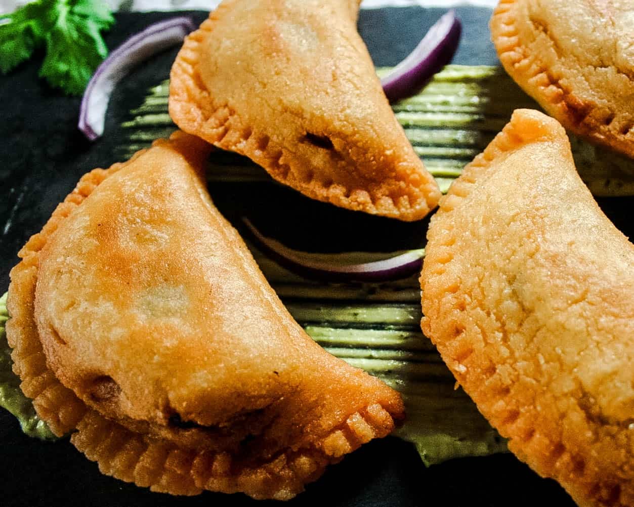 A plate with four fried empanadas on it.