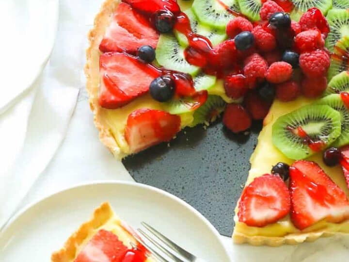 A fruit tart with strawberries and kiwis on a plate.