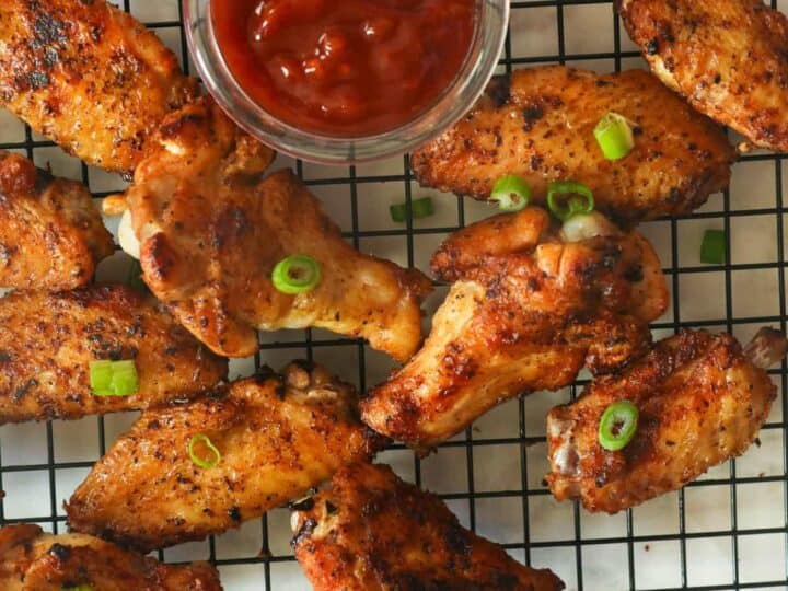 Grilled chicken wings on a wire rack with ketchup.
