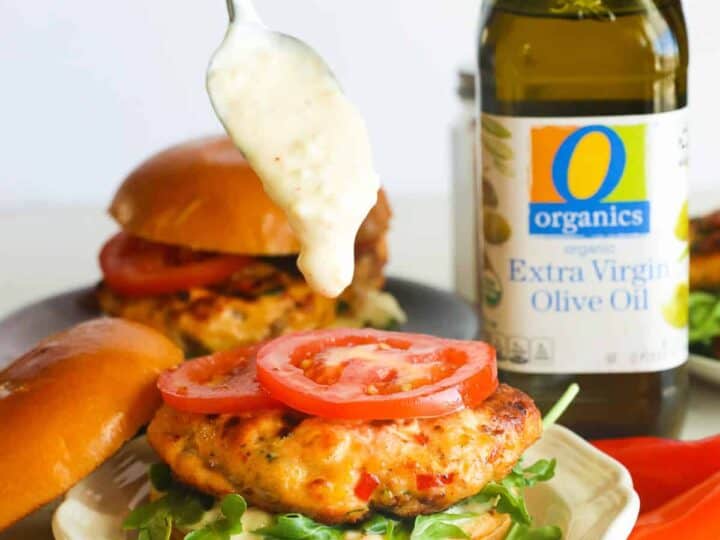 A chicken burger is being dipped in olive oil.