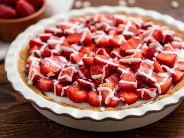 A pie with strawberries and icing on top.