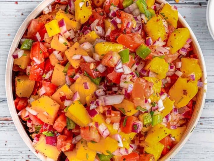 A bowl of salsa with tomatoes, onions, and lemons.