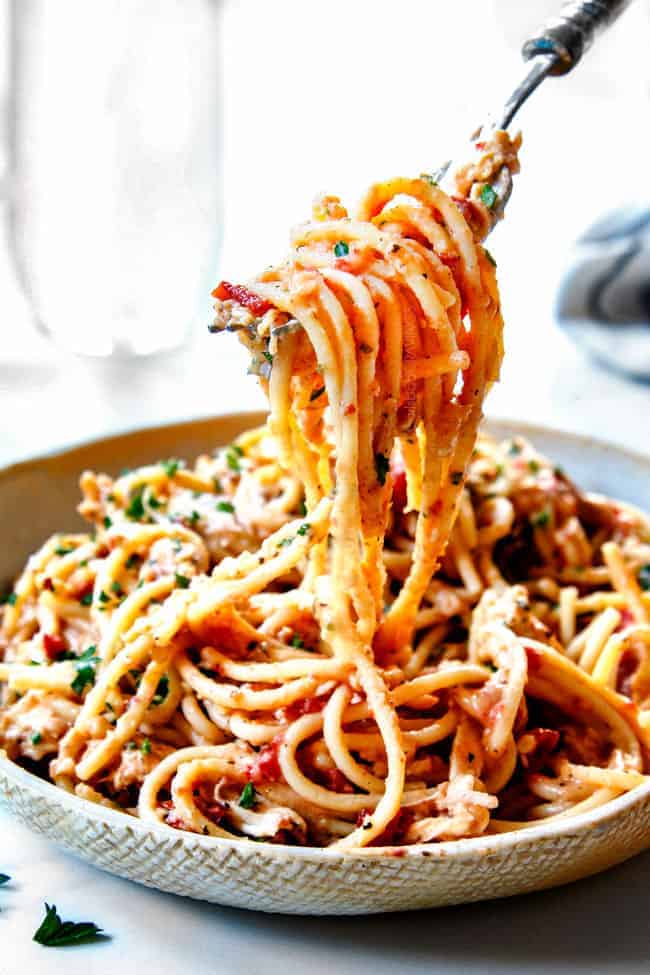 A fork is being used to pick up spaghetti on a plate.