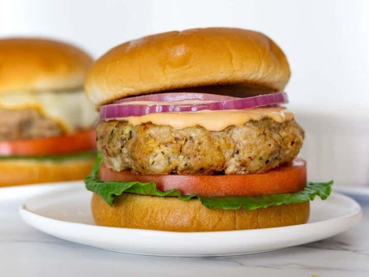 Two chicken burgers on a white plate.