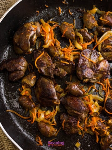 Sautéed chicken livers with onions and carrots in a frying pan.