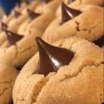 Close-up of peanut butter blossom cookies topped with chocolate kisses, arranged neatly in rows.