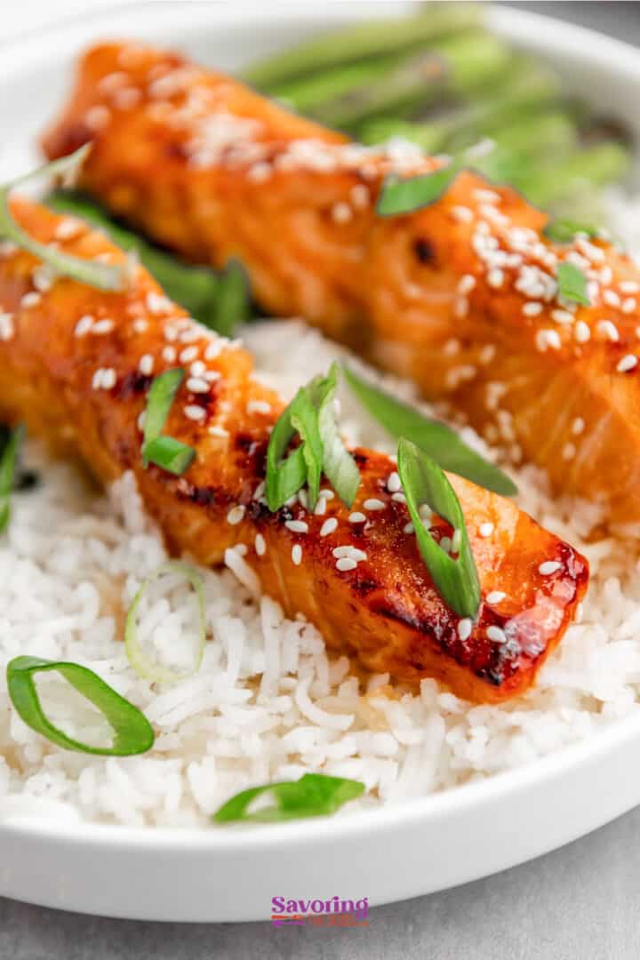 Air Fryer Glazed salmon over white rice garnished with sesame seeds and green onions.