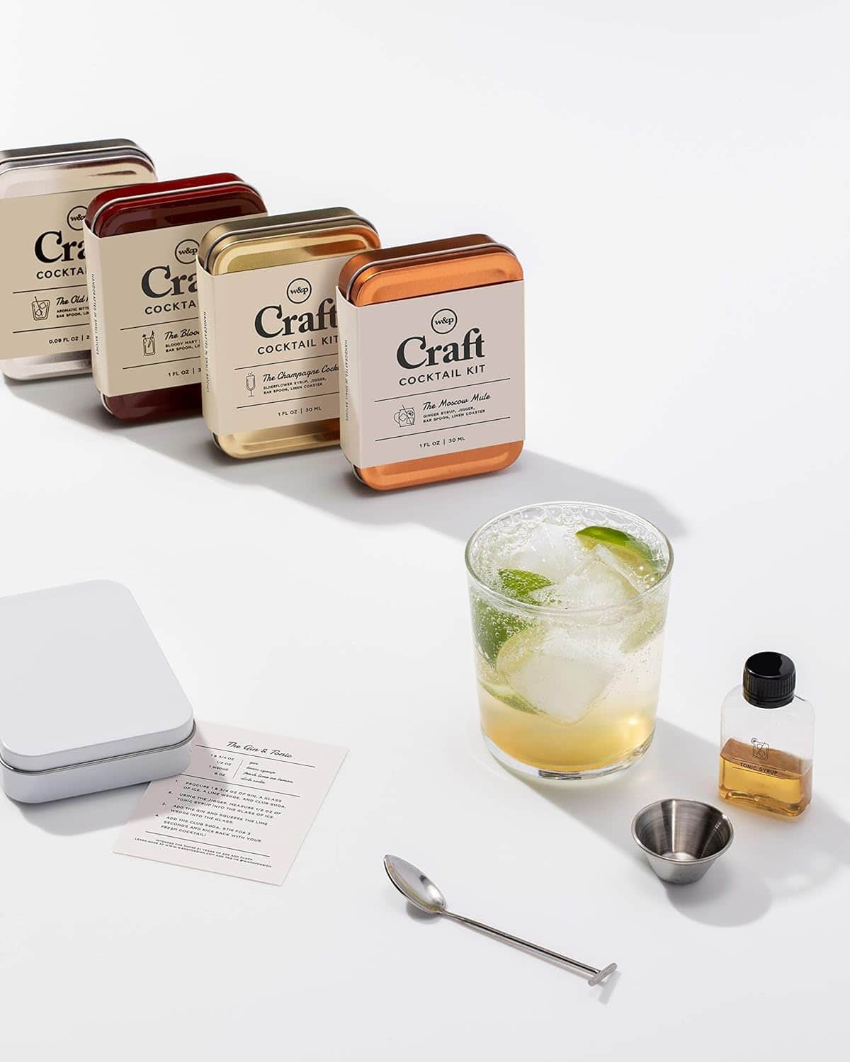 A perfect Father's Day gift: this cocktail kit includes five metal tins, a glass with a drink and lime, a recipe card, spoon, jigger, and cocktail mixโeverything Dad needs for a classic toast.