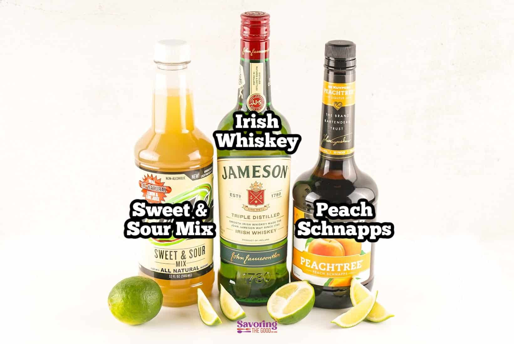 Bottles of sweet and sour mix, Irish whiskey, and peach schnapps are arranged side by side, with lime wedges and lime halves placed in front of them on a white background.