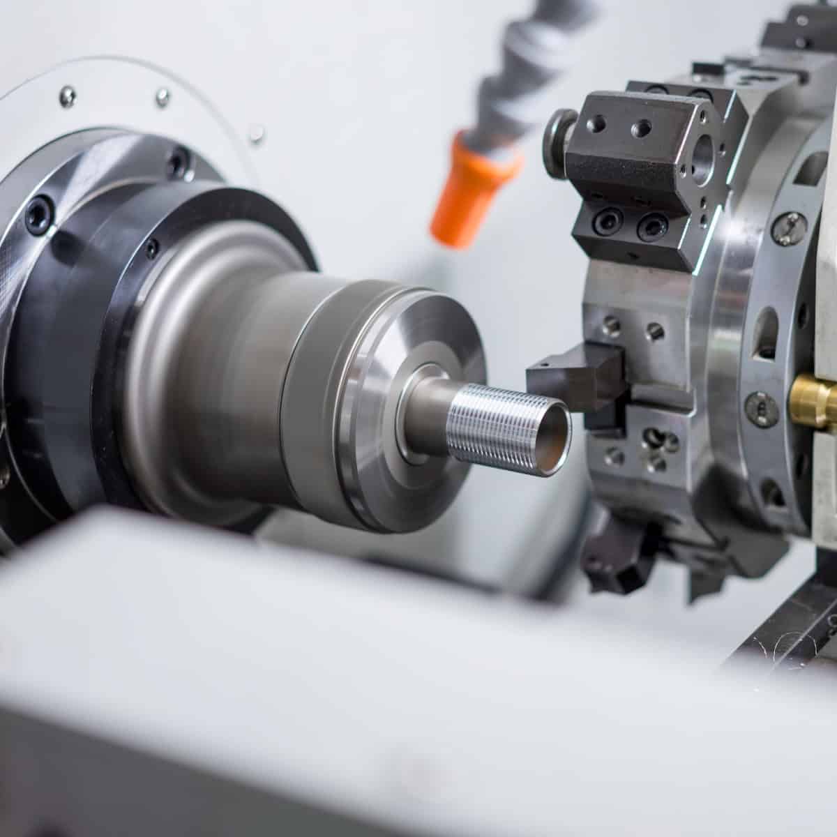 Close-up view of a CNC lathe machine in operation, precisely machining a metal part with a rotating spindle and cutting tool.