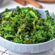 A bowl of crispy air-fried kale chips on a table.