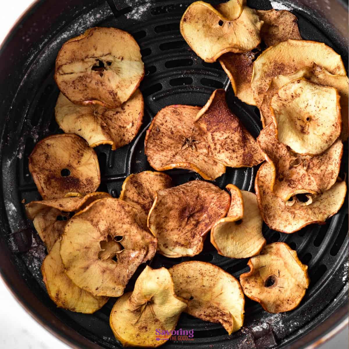 Air fried apple chips, seasoned to perfection, are arranged neatly in an air fryer basket.