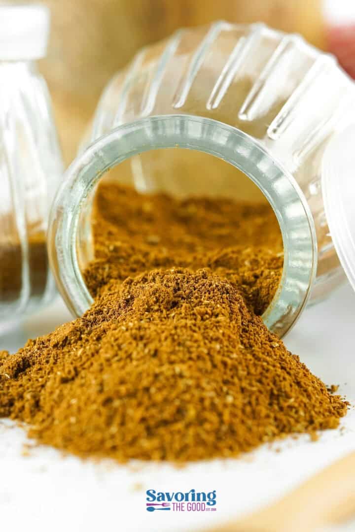 An overturned spice jar with ground seasoning spilling out onto a surface. The label reads "Savoring the Good.