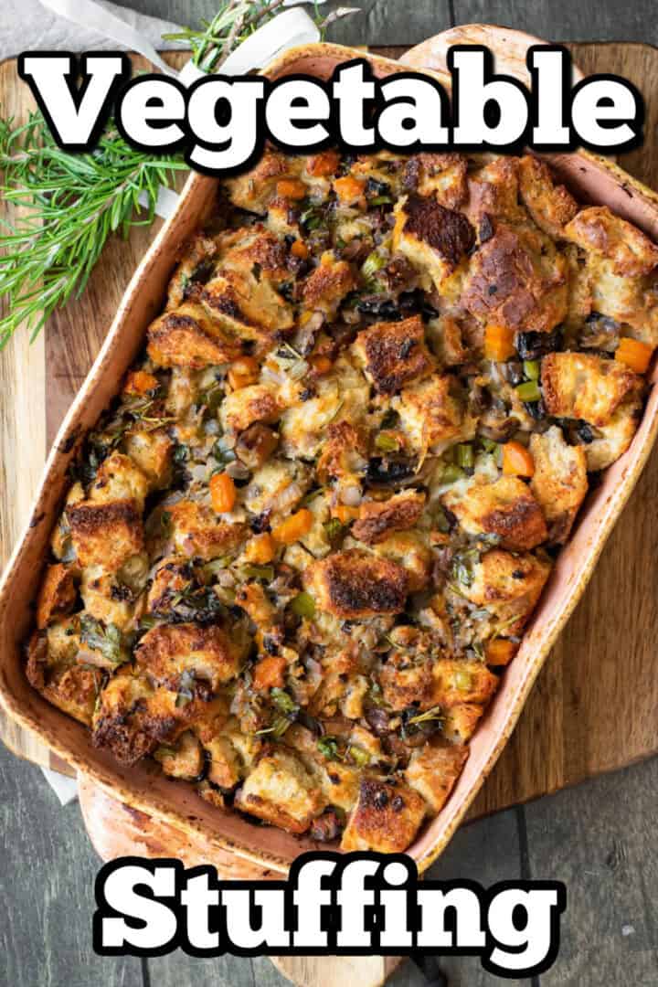 A baked dish of vegetable stuffing with cubed bread, herbs, and vegetables displayed in a rectangular tray. The words "Vegetable Stuffing" are written above and below the tray in large white text.