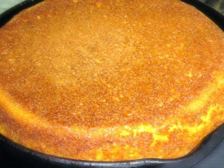 A golden brown cornbread baked in a cast iron skillet.