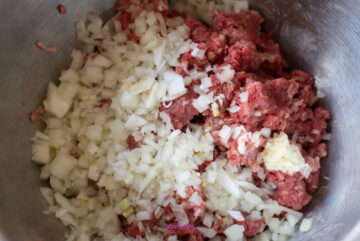 A bowl containing chopped onions, minced garlic, and raw ground meat, great for perfecting your own IKEA Swedish meatballs recipe.