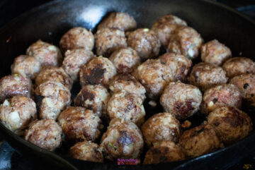 A cast-iron skillet filled with cooked meatballs, browned on the outside and appearing to be well-seasoned, reminiscent of an IKEA Swedish meatballs recipe.