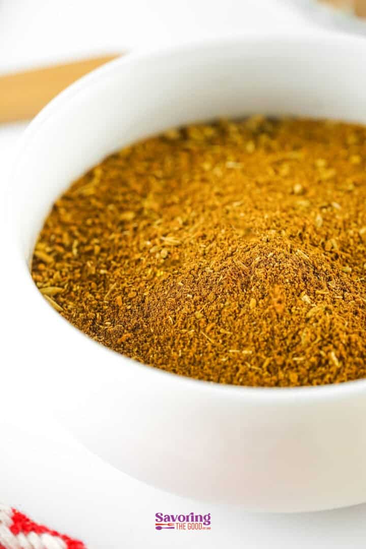 A white bowl filled with a blend of ground spices, prominently featuring the rich aromas of Chinese five spice.