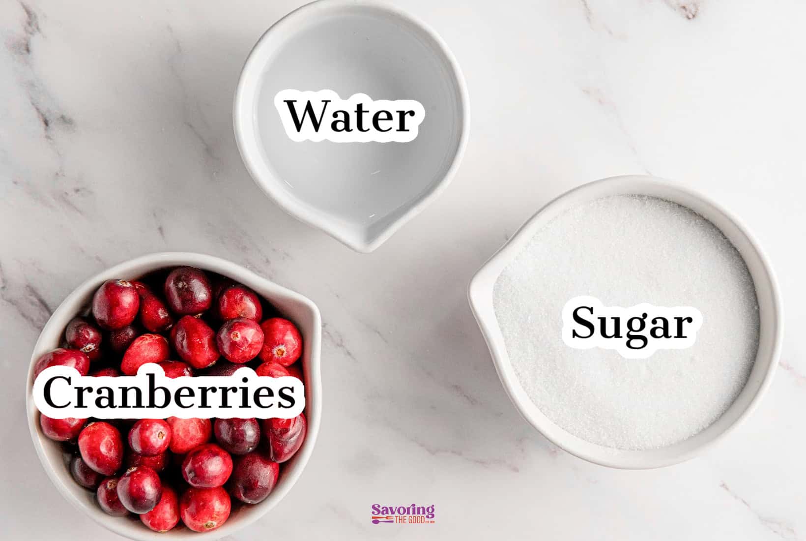 Top view of three bowls on a marble surface, featuring fresh cranberries, water, and sugar, each labeled accordingly. Perfect for making sugared cranberries.