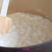 A spatula stirs a pot of cooking marshmallows, bringing to mind the gooey delight of golden graham s'mores.