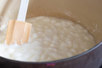 A spatula stirs a pot of cooking marshmallows, bringing to mind the gooey delight of golden graham s'mores.