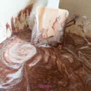 Mixing chocolate and cream with a spatula in a bowl, creating a luscious blend reminiscent of golden graham s'mores.