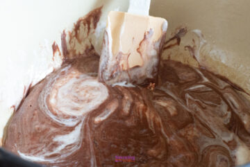 Mixing chocolate and cream with a spatula in a bowl, creating a luscious blend reminiscent of golden graham s'mores.