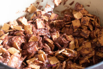 Close-up of cereal squares mixed with melted chocolate in a bowl.