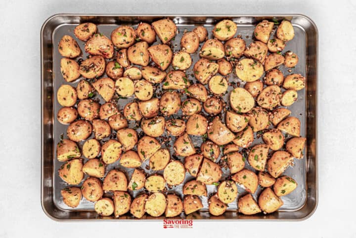A baking sheet filled with roasted baby potatoes, seasoned to perfection with a blend of fragrant herbs and spices.