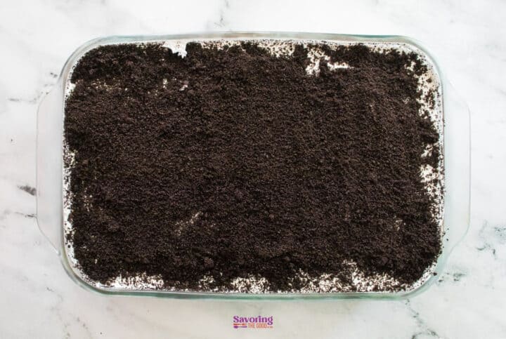 A dessert dish reminiscent of chocolate lasagna, topped with a layer of crushed chocolate cookies.