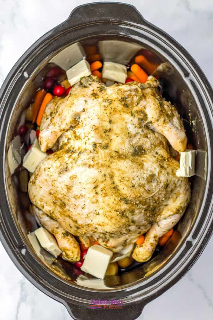 Savor a delightful Christmas chicken, slow-cooked to perfection with carrots, cranberries, potato chunks, and generous pats of butter.