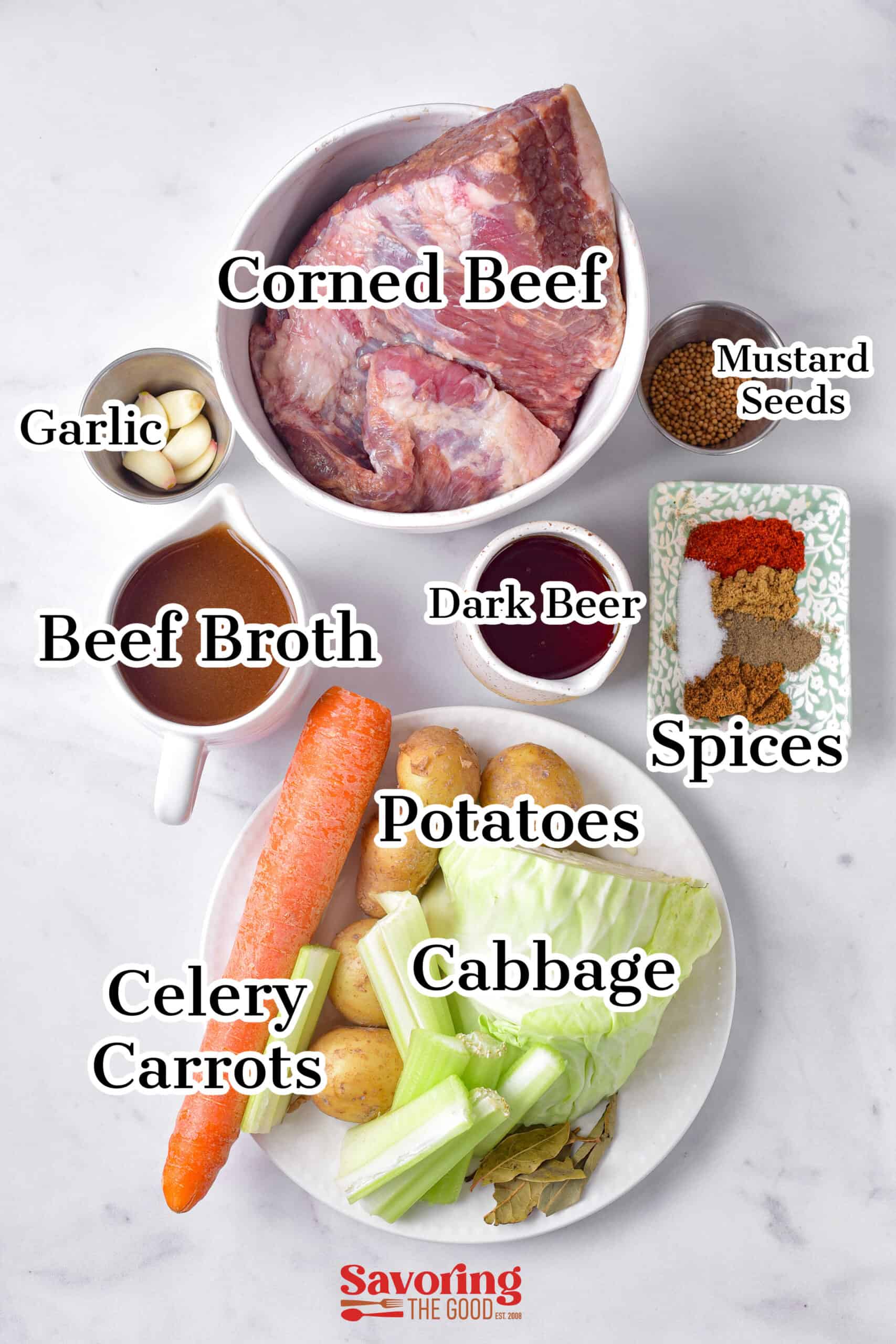 Ingredients for corned beef: corned beef, beef broth, dark beer, garlic, mustard seeds, spices, potatoes, cabbage, carrots, and celery displayed on a table.