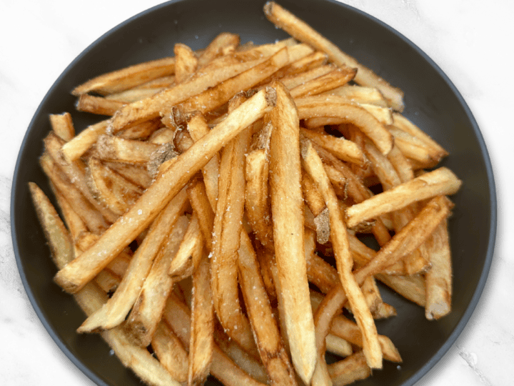 A bowl filled with crinkle-cut French fries seasoned with salt. Text at the top reads, "Grassfed Beef Tallow French Fries Recipe.