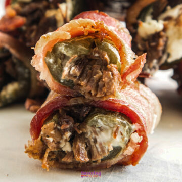 Close-up of Texas Twinkies—bacon-wrapped jalapeños stuffed with cream cheese and shredded meat—stacked invitingly on a plate.
