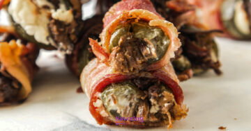 Close-up of Texas Twinkies—bacon-wrapped jalapeño poppers stuffed with savory beef and creamy cheese—resting on a white surface.