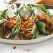 Texas Twinkies are green peppers stuffed with shredded meat and topped with cream cheese, served on a pristine white plate.