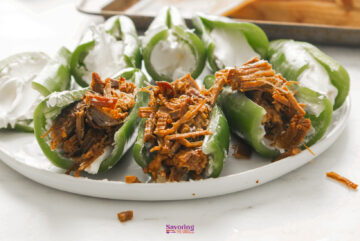 Texas Twinkies are green peppers stuffed with shredded meat and topped with cream cheese, served on a pristine white plate.