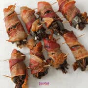 Bacon-wrapped Texas Twinkies, speared with toothpicks, are artfully arranged on a crisp white surface.