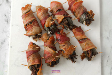 Bacon-wrapped Texas Twinkies, speared with toothpicks, are artfully arranged on a crisp white surface.