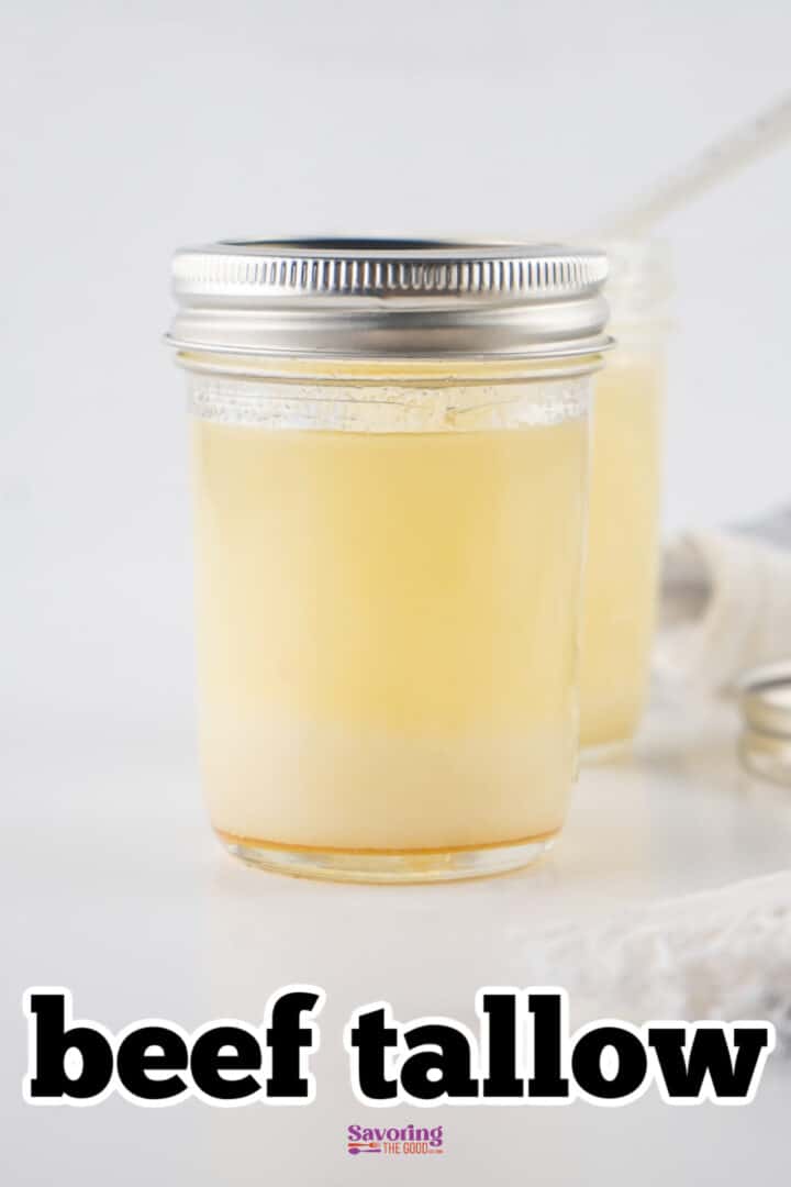 A glass jar filled with beef tallow, with a silver lid and a white background. A second jar is partially visible in the background.