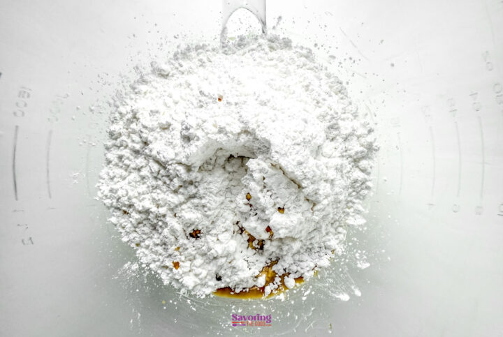 A mound of white powdered sugar sits in a clear mixing bowl.