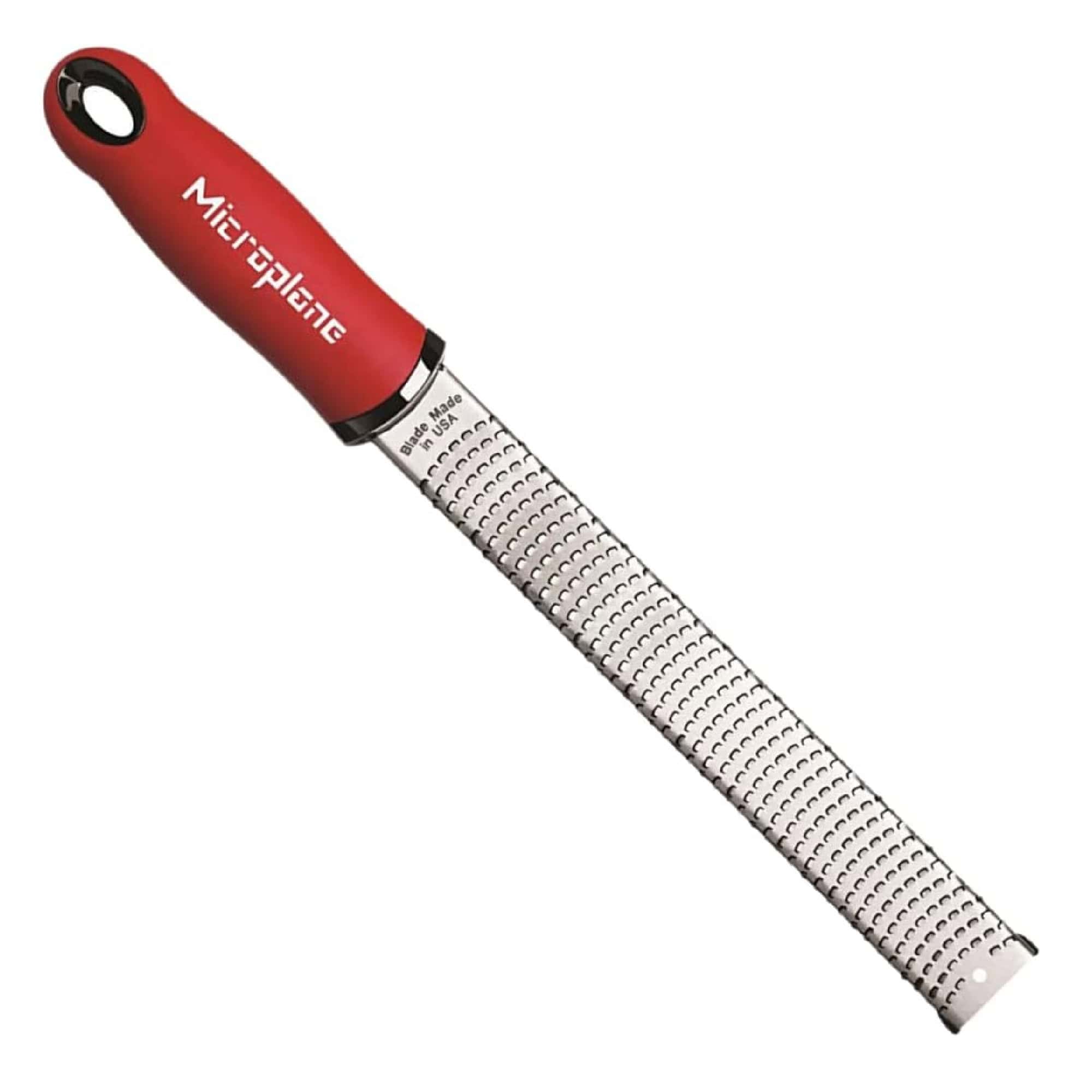 A red-handled Microplane grater with a long, stainless steel blade featuring fine grating surfaces.