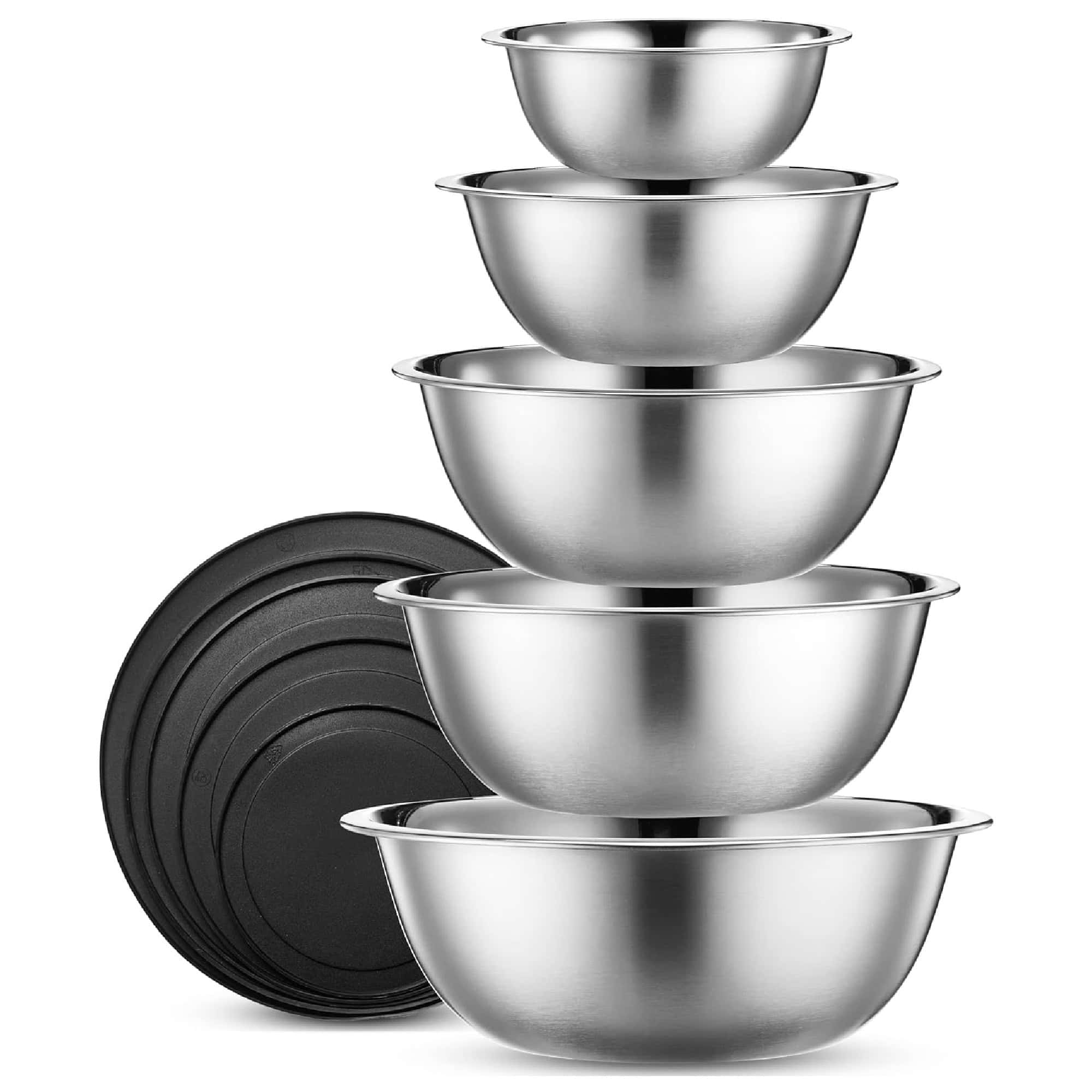 A stack of five stainless steel mixing bowls of varying sizes with four black lids beside them.