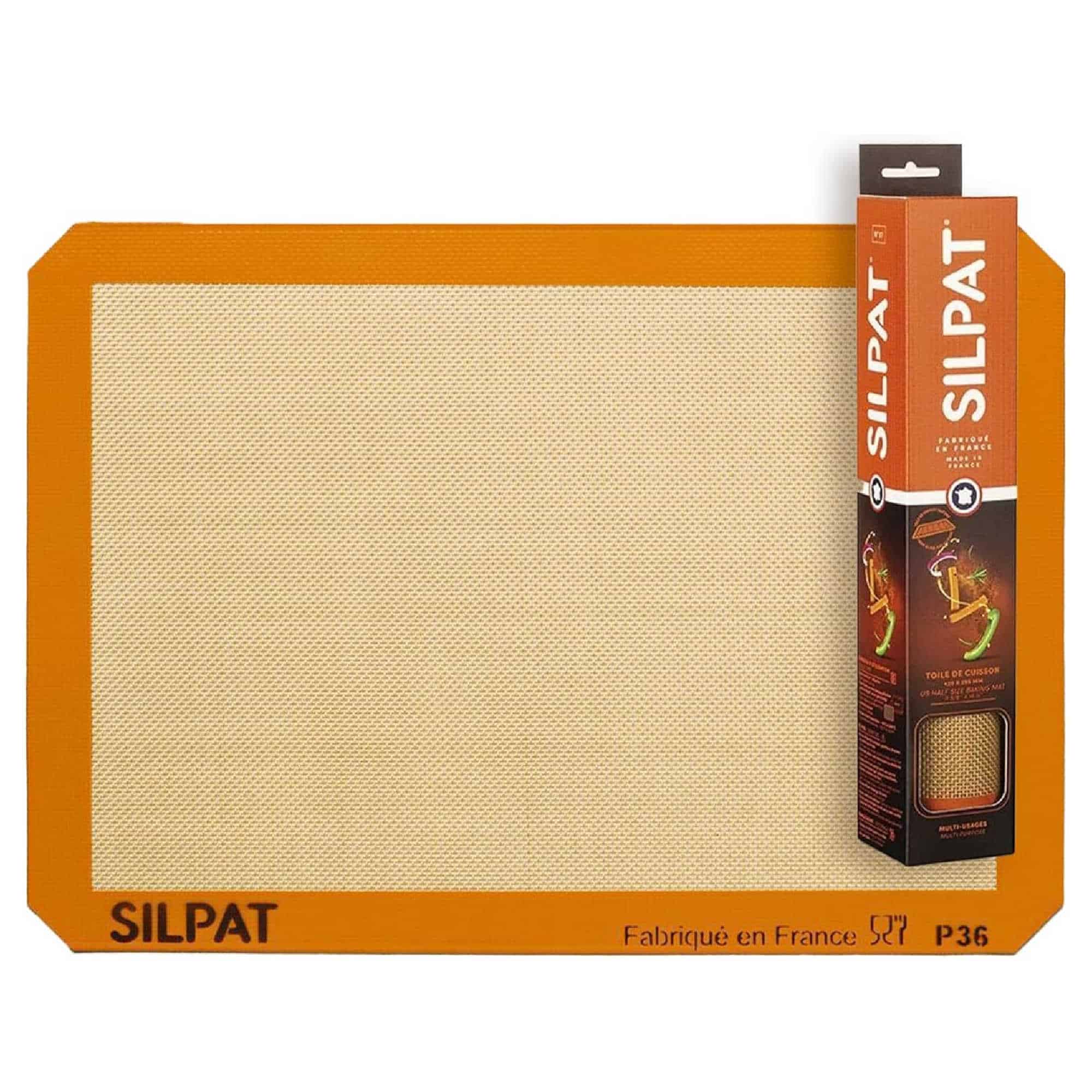 Silicone baking mat with orange border, branded as Silpat, alongside its packaging box with graphics and product information. Made in France.