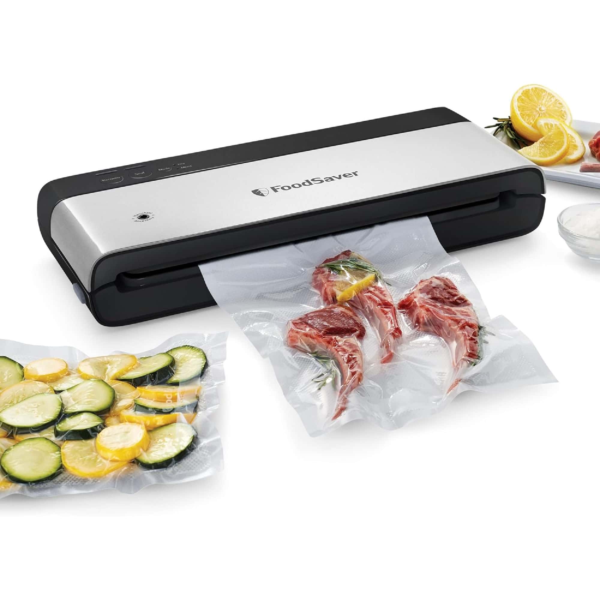 A vacuum sealer sealing a bag of meat. Beside it, there are vacuum-sealed bags of sliced vegetables and lemons.