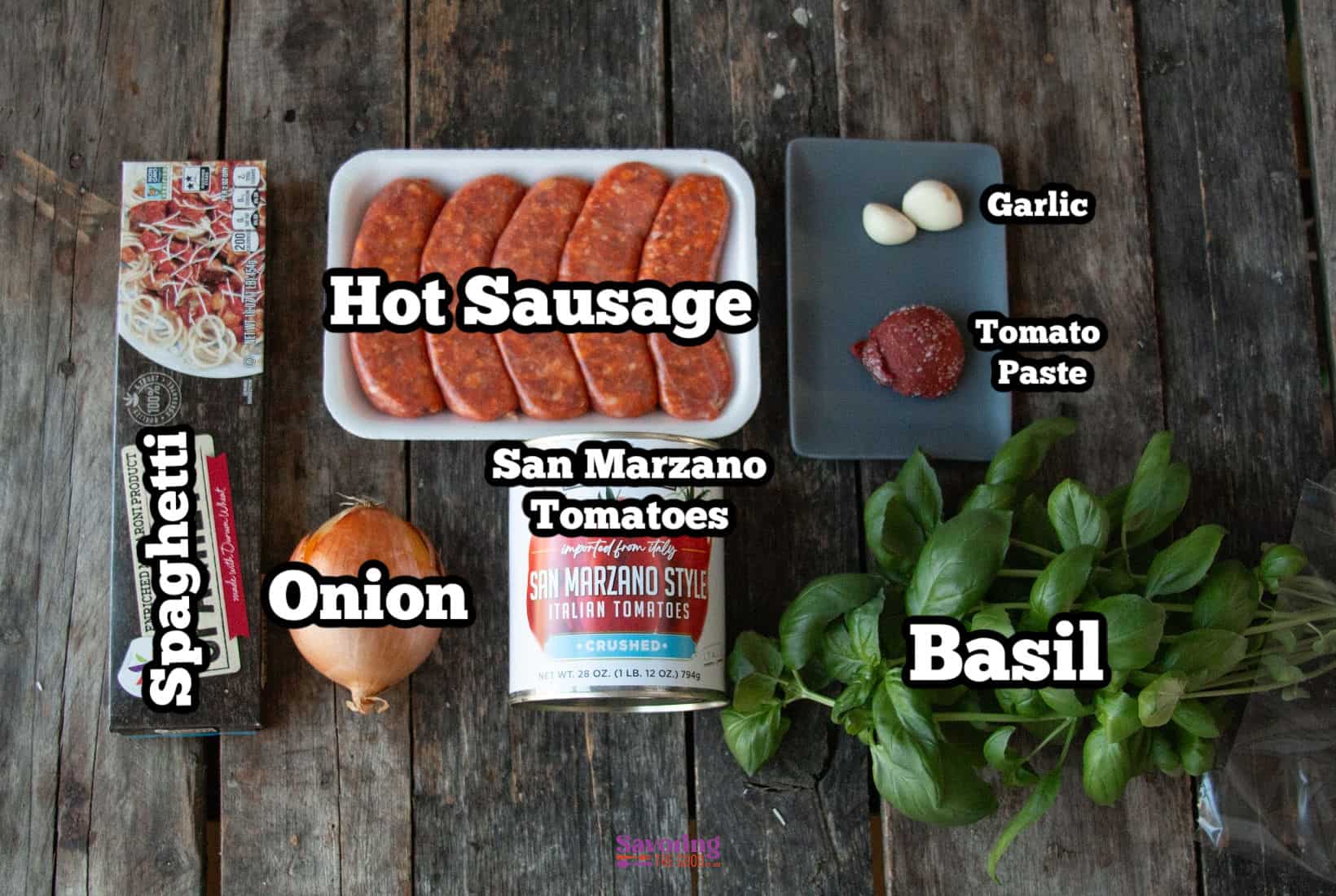 On a rustic wooden table, the essentials for a hearty calabrese pasta come together: spaghetti, onion, spicy hot sausage, rich San Marzano tomatoes, aromatic garlic, robust tomato paste, and fresh basil.