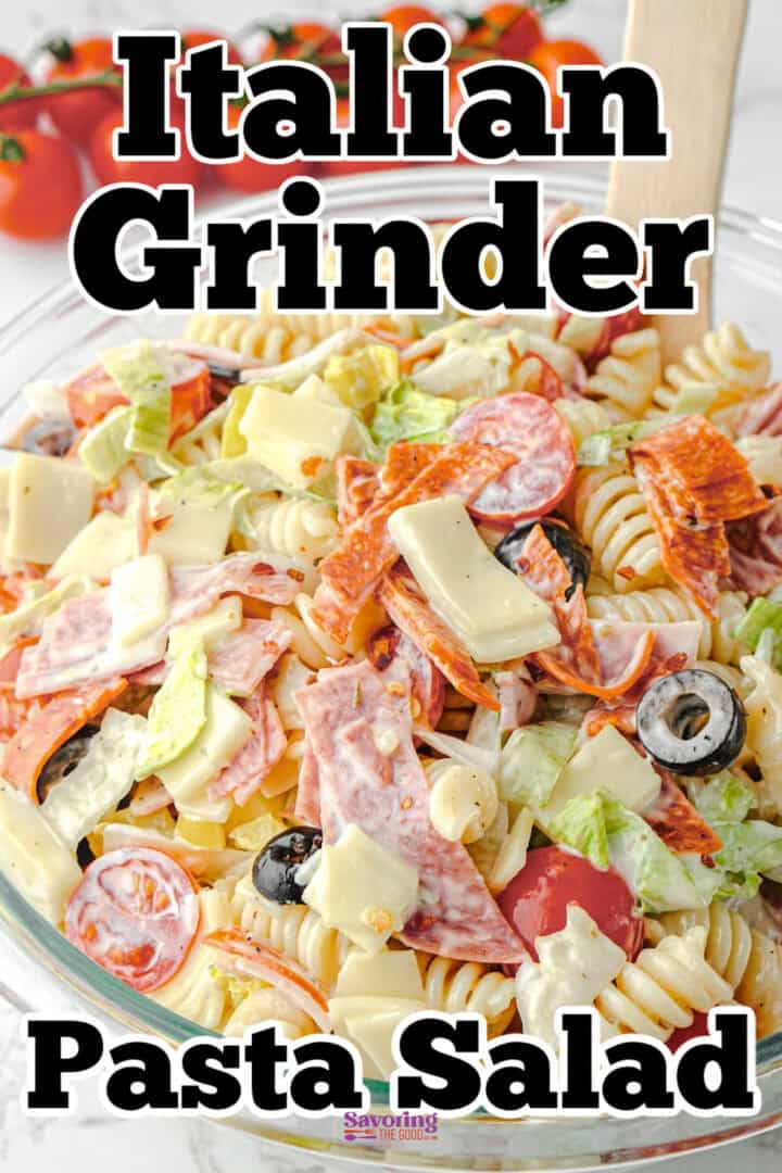 A bowl of Italian grinder pasta salad with rotini noodles, sliced deli meats, cheese, olives, and vegetables, with a wooden spoon. Text overlay reads "Italian Grinder Pasta Salad.